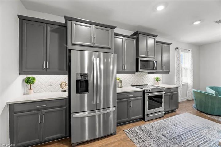Open kitchen with WOOD-LOOK TILE FLOOR, upgraded self-cleaning, glass smooth top KITCHEN-AID RANGE, tile backsplash, and UNDER CABINET LIGHTING.