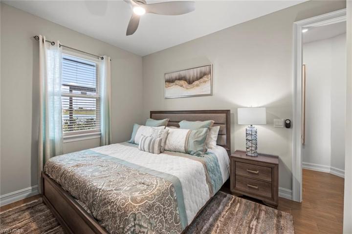 Bedroom 2 with new WOOD-LOOK TILE FLOOR (October 2022), new ceiling fan/light (October 2022), window blinds, and water/golf course view.