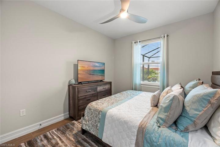Bedroom 2 with new WOOD-LOOK TILE FLOOR (October 2022), new ceiling fan/light (October 2022), window blinds, and water/golf course view.