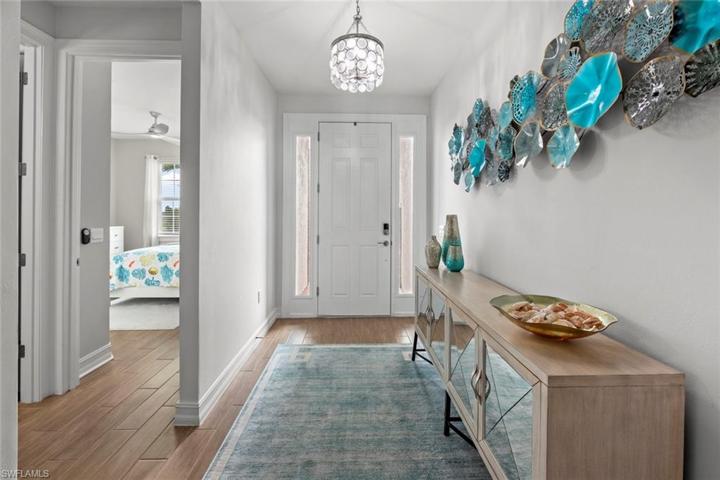 Large inviting entry with glass sidelight windows bring extra light into the space. Upgrades include wood-look tile floor, and new custom chandelier (November 2022).