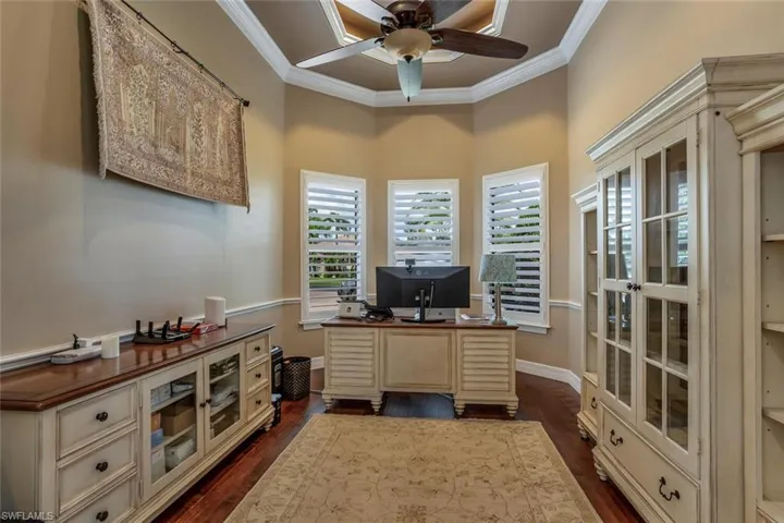 Office space with dark hardwood / wood-style floors, crown molding, and a wealth of natural light