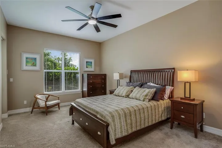 Secondary owner bedroom with light colored carpet and ceiling fan