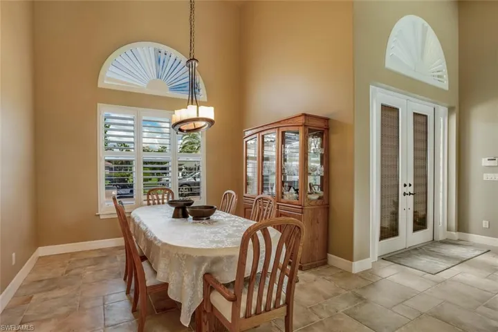Formal dining room with chandelier, entry French doors and a high ceiling