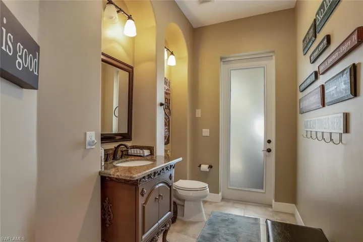 Pool bathroom with tile patterned floors, vanity, and toilet