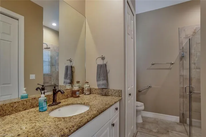 Bathroom with tile patterned flooring, vanity, toilet, and a shower with glass door