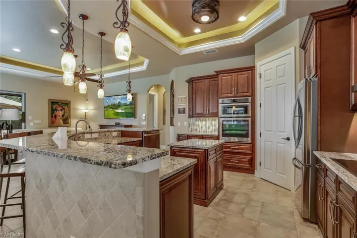 Kitchen with pendant lighting, a breakfast bar, raised coffer ceiling, appliances with stainless steel finishes, induction cooktop and a large island