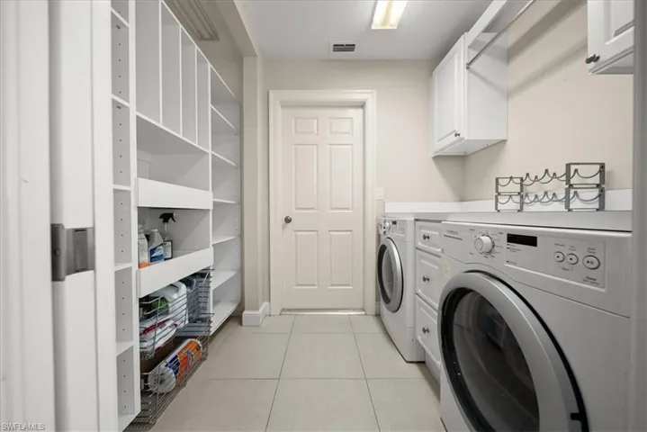 Washroom featuring cabinet space, washer and clothes dryer, and light tile patterned floors