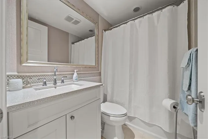Bathroom featuring vanity, tasteful backsplash, and a shower with shower curtain