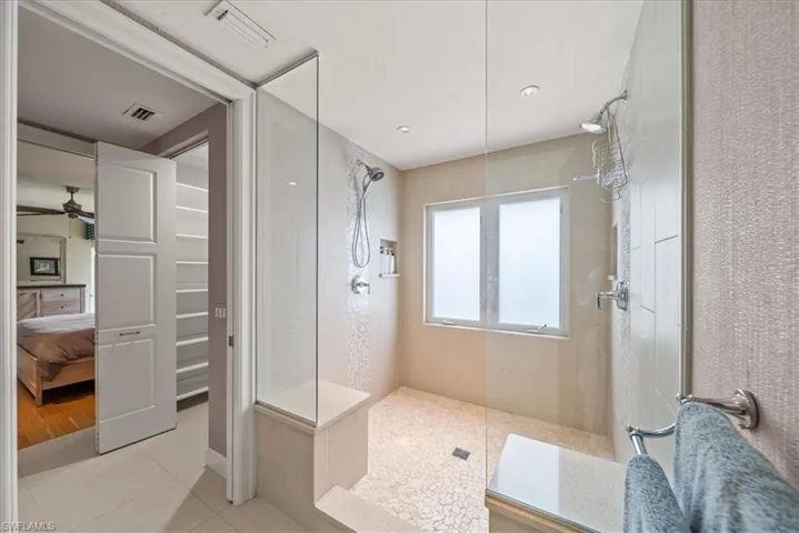 Ensuite bathroom featuring a walk in shower, tile patterned flooring, and a ceiling fan