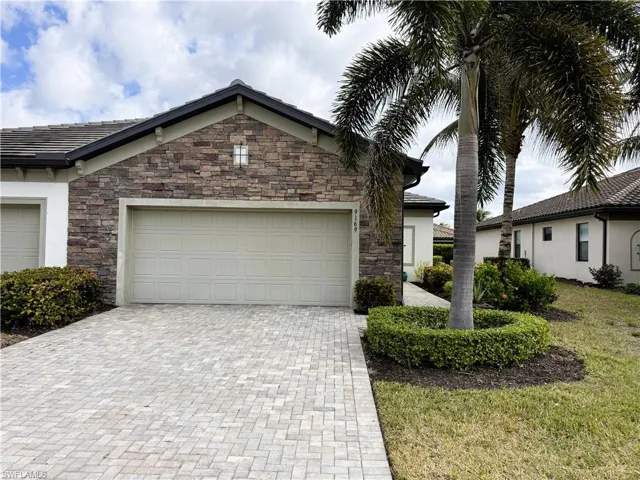 View of front of home featuring stone siding, decorative driveway, stucco siding, and a garage