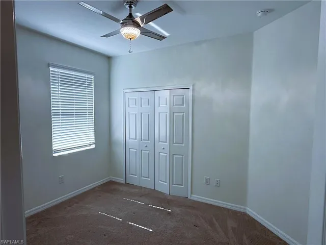 Unfurnished bedroom with carpet, a closet, and a ceiling fan
