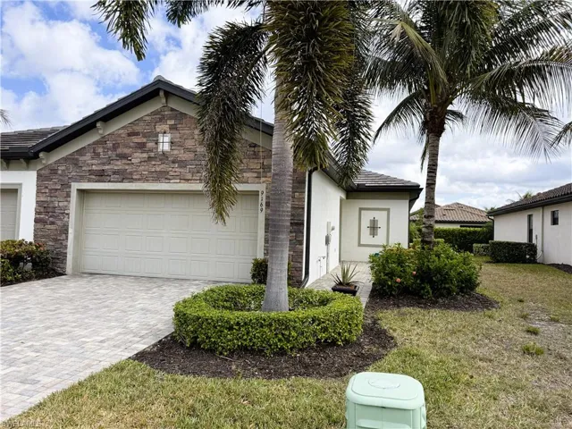 Single story home with stone siding, decorative driveway, stucco siding, a garage, and a front yard