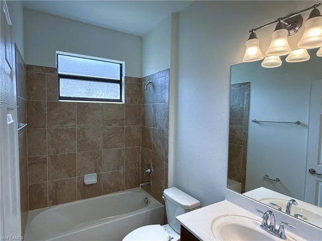 Full bathroom with shower / bathtub combination, vanity, and a textured wall