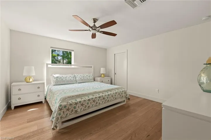 Bedroom featuring a ceiling fan, light wood-style flooring, visible vents, and baseboards