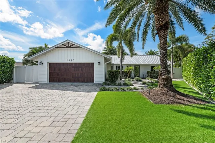 View of front of property with a garage, a gate, a front lawn, and decorative driveway