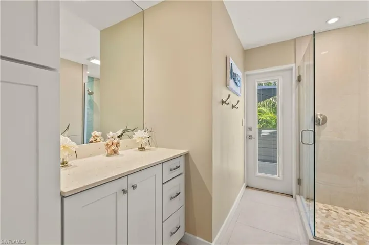Bathroom featuring baseboards, tile patterned flooring, vanity, a shower stall, and recessed lighting