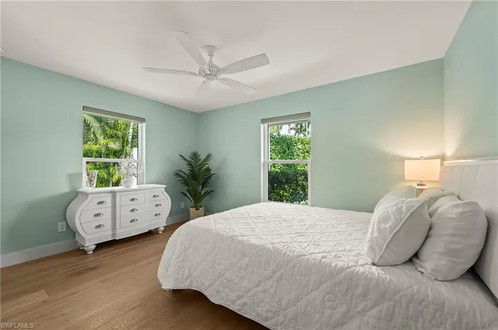 Bedroom with a ceiling fan, multiple windows, baseboards, and wood finished floors
