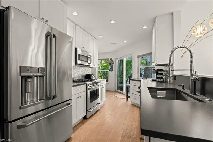 Kitchen with dark countertops, tasteful backsplash, white cabinetry, and stainless steel appliances