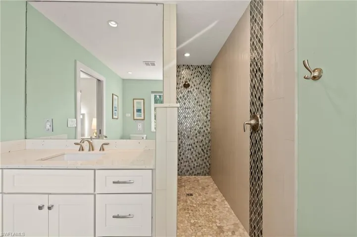 Full bathroom with vanity, walk in shower, visible vents, and recessed lighting