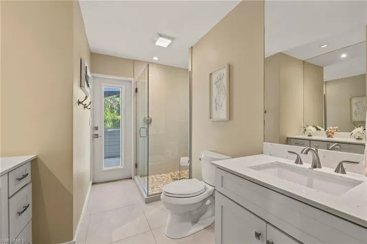Full bath featuring toilet, a stall shower, vanity, tile patterned flooring, and baseboards