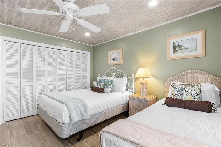 Bedroom with an office area, access to exterior, wood finished floors, a ceiling fan, and wooden ceiling - Virtually Edited Image