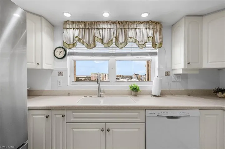 Kitchen featuring stainless steel refrigerator, dishwasher, white cabinets, and recessed lighting - Virtually Edited Image