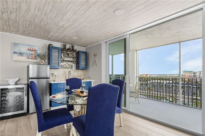 Dining area with wine cooler, floor to ceiling windows, light wood-type flooring, and wooden ceiling - Virtually Edited Image