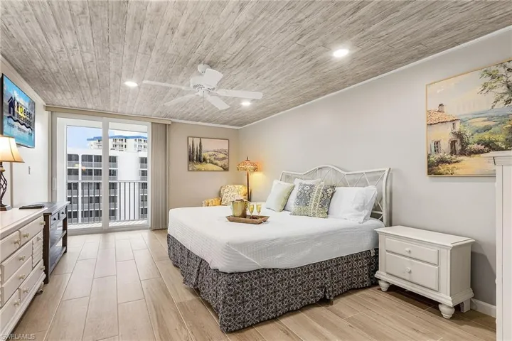 Bedroom featuring wood finish floors, ceiling fan, expansive windows, recessed lighting, and wood ceiling - Virtually Edited Image