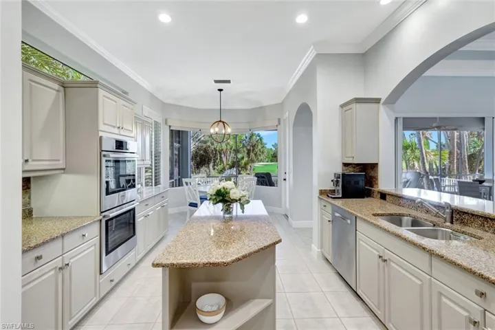 Kitchen with light stone countertops, sink, stainless steel appliances, and ornamental molding