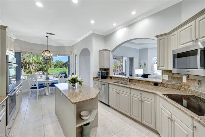 Kitchen with plenty of natural light, light stone counters, decorative backsplash, and appliances with stainless steel finishes