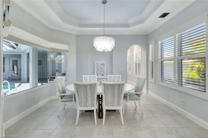 Dining room with a notable chandelier, plenty of natural light, ornamental molding, and light tile patterned floors
