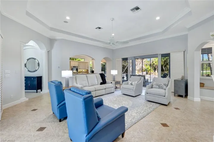Living room with ceiling fan, a healthy amount of sunlight, ornamental molding, and a tray ceiling