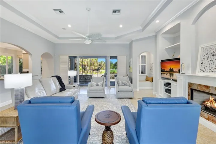 Living room featuring a fireplace, a wealth of natural light, ornamental molding, and ceiling fan