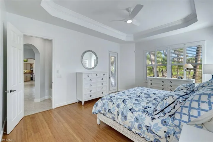 Bedroom with hardwood / wood-style flooring, a raised ceiling, ceiling fan, tray ceiling and ornamental molding