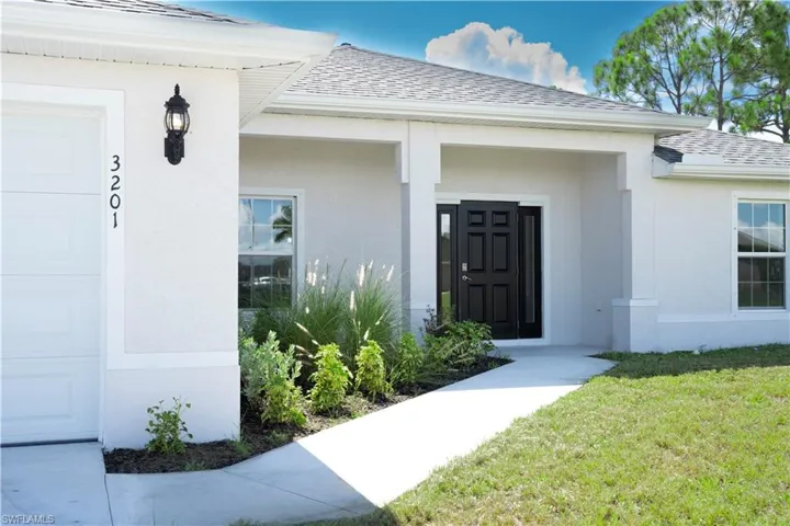 Doorway to property with a garage and a yard