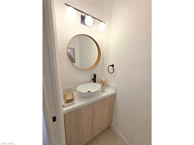 Bathroom featuring vanity, a textured wall, and light tile patterned floors