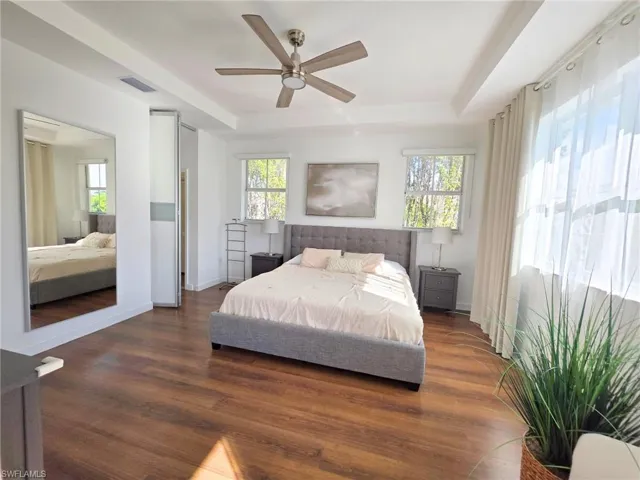 Bedroom featuring a tray ceiling, wood finished floors, and a ceiling fan