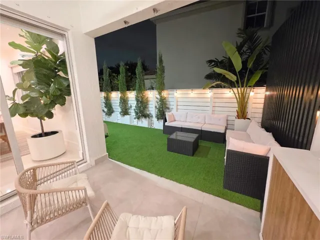 Patio at night with outdoor furniture, a fenced backyard, and a patio area