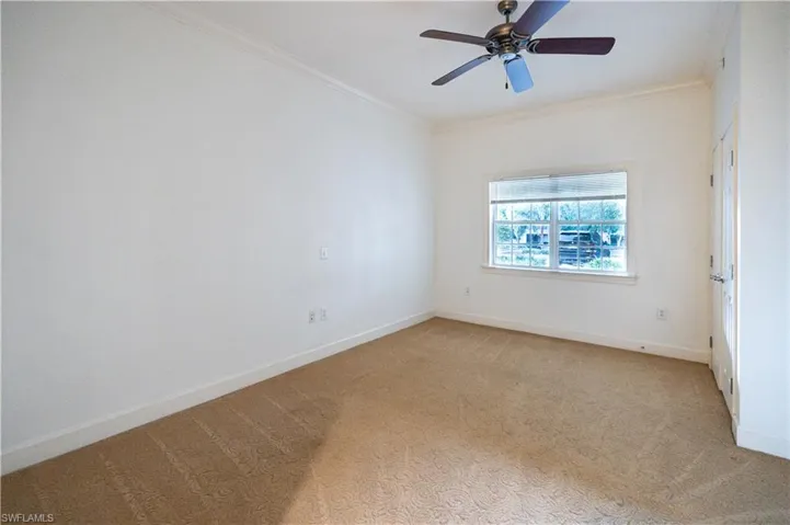 Carpeted spare room featuring ornamental molding and ceiling fan