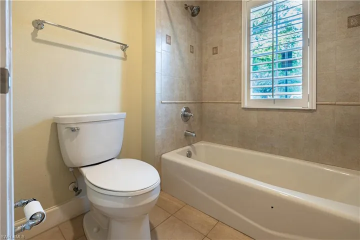 Bathroom with tile flooring, toilet, and tiled shower / bath combo