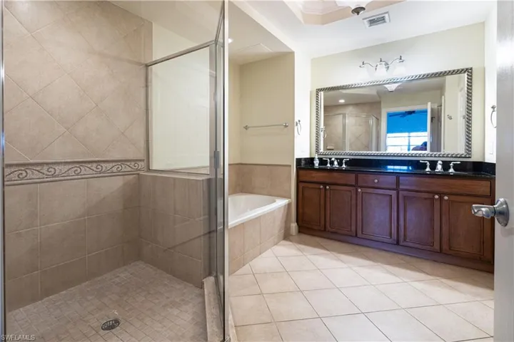 Bathroom with dual bowl vanity, tile flooring, and separate shower and tub