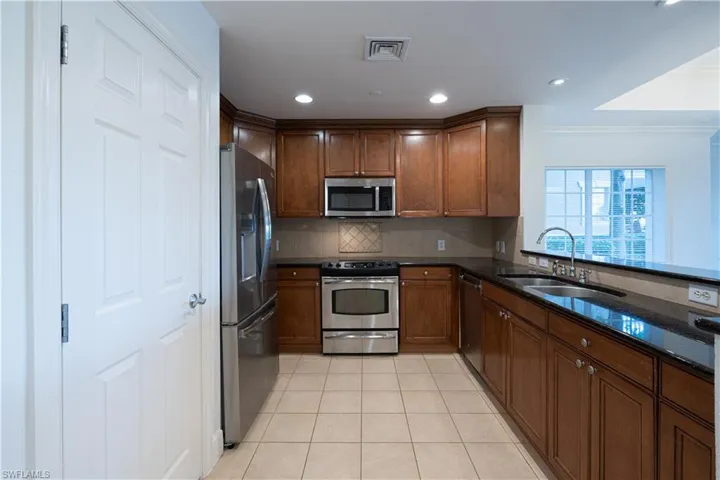 Kitchen featuring crown molding, stainless steel appliances, backsplash, sink, and light tile floors
