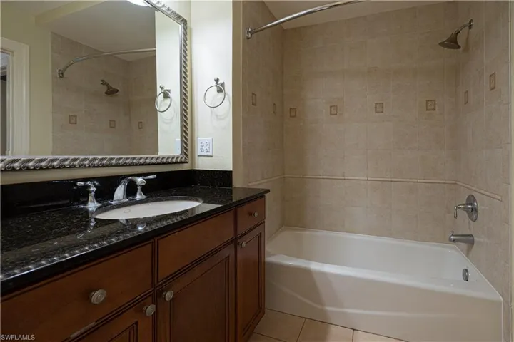 Bathroom featuring tiled shower / bath, tile flooring, and vanity