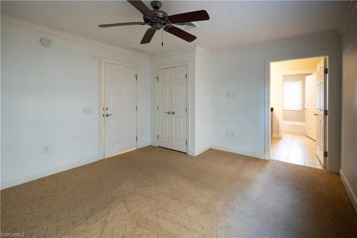 Carpeted spare room featuring ornamental molding and ceiling fan
