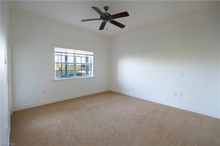 Empty room with ceiling fan, carpet floors, and crown molding