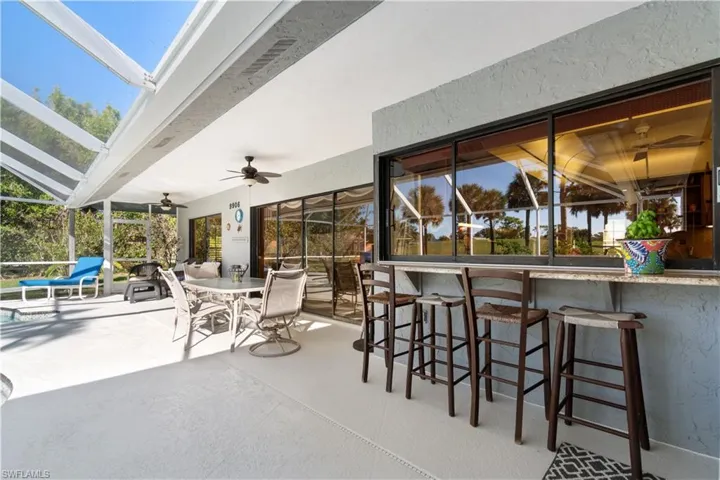 View of patio featuring ceiling fan, a lanai, and a bar