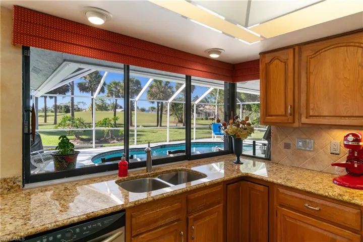 Kitchen with light stone countertops, stainless steel dishwasher, plenty of natural light, and sink