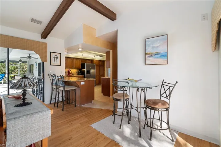 Dining room with lofted ceiling with beams and light hardwood / wood-style flooring