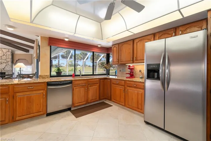 Kitchen featuring light stone countertops, appliances with stainless steel finishes, tasteful backsplash, ceiling fan, and light tile patterned floors