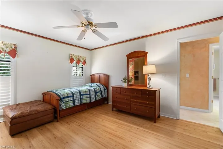 Bedroom featuring ceiling fan, wood-type flooring, and multiple windows
